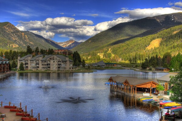 A lakeside hotel with a dock, a building with multiple floors, and a mountain backdrop.