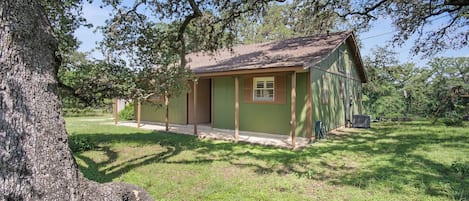 A single-story building with a green exterior and a brown roof, surrounded by grass and trees.