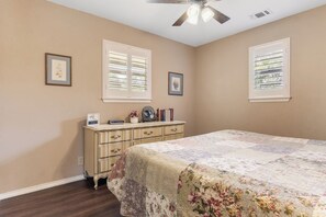 A bedroom with a bed, dresser, two windows with blinds, and a ceiling fan. - Lambert Park | Cozy 2BR Near Bandera Honky-Tonks (Bandera)