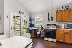 A kitchen with wooden cabinets, a stove, a microwave, and a dining table with chairs.