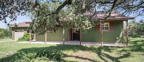 A single-story house with a covered porch, a garage, and a lawn.