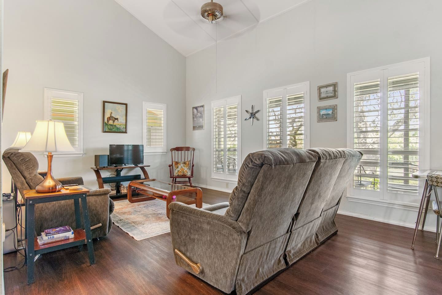 A spacious living room with a large gray sofa, a television, and a fireplace.