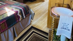 A cabin-style room with a bed, dresser, and a sink with a towel.