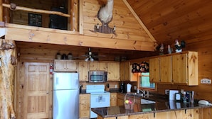A rustic wooden cabin kitchen with a refrigerator, microwave, stove, and wooden bar stools. - 'Endless View' from the Top of Sunrock Mountain (Blue Ridge)