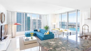 Una sala de estar moderna con un sofá azul, un comedor y una cocina con una isla grande.
