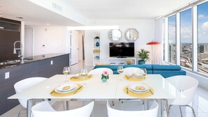 Una sala de estar moderna con comedor, televisor y vistas a la ciudad.
