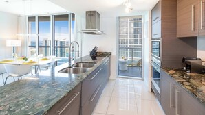 Una cocina moderna con una isla grande, electrodomésticos de acero inoxidable y vistas a la ciudad.