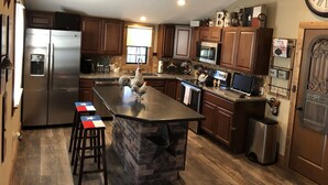 A spacious kitchen with a large island, stainless steel appliances, and wooden cabinets. - Cozy Cabin in the Woods - Lake Livingston, Texas (Livingston)