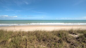 Een strand met heldere lucht en golven.