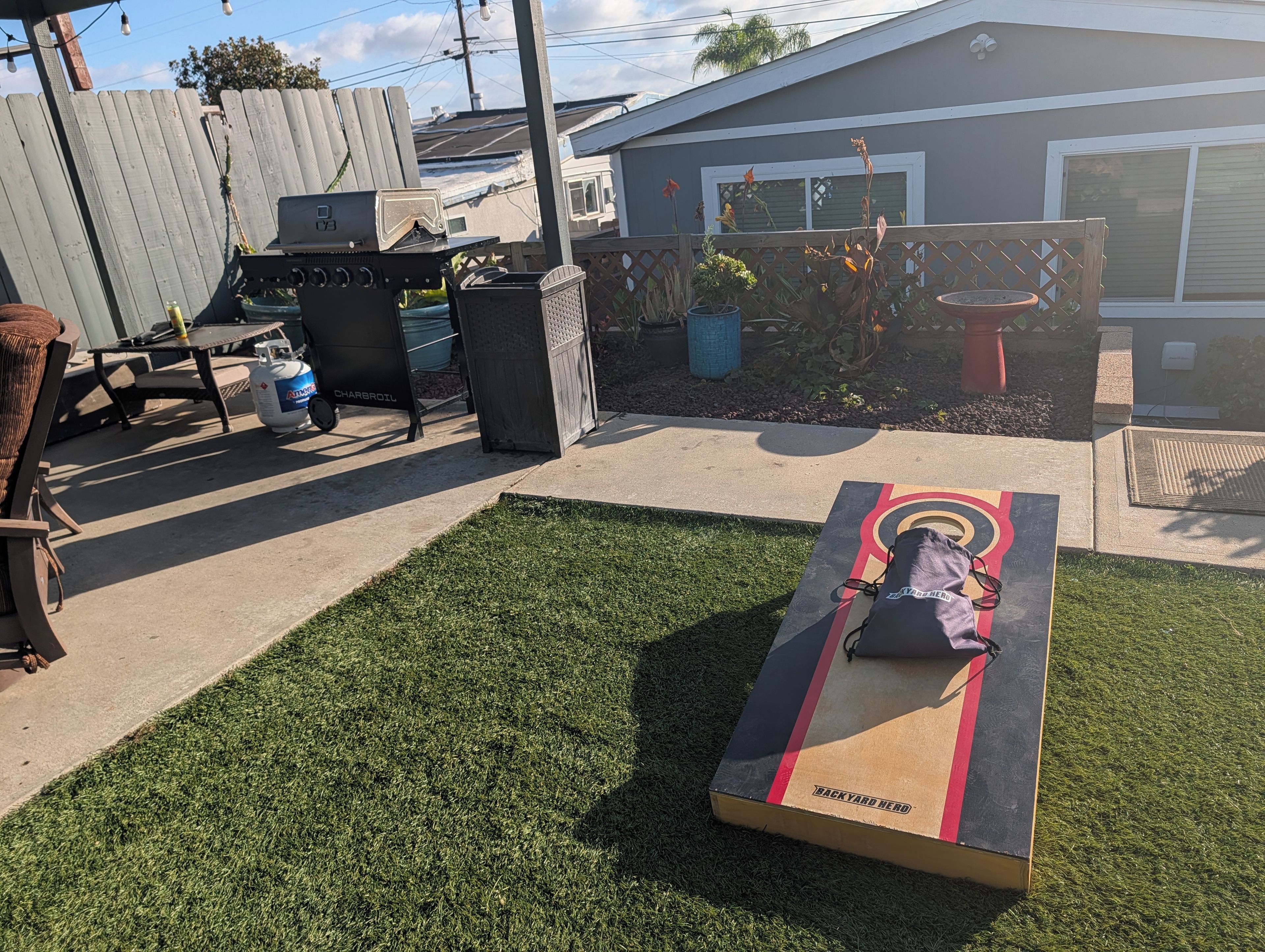 A backyard with a barbecue grill, a table, and a lawn.
