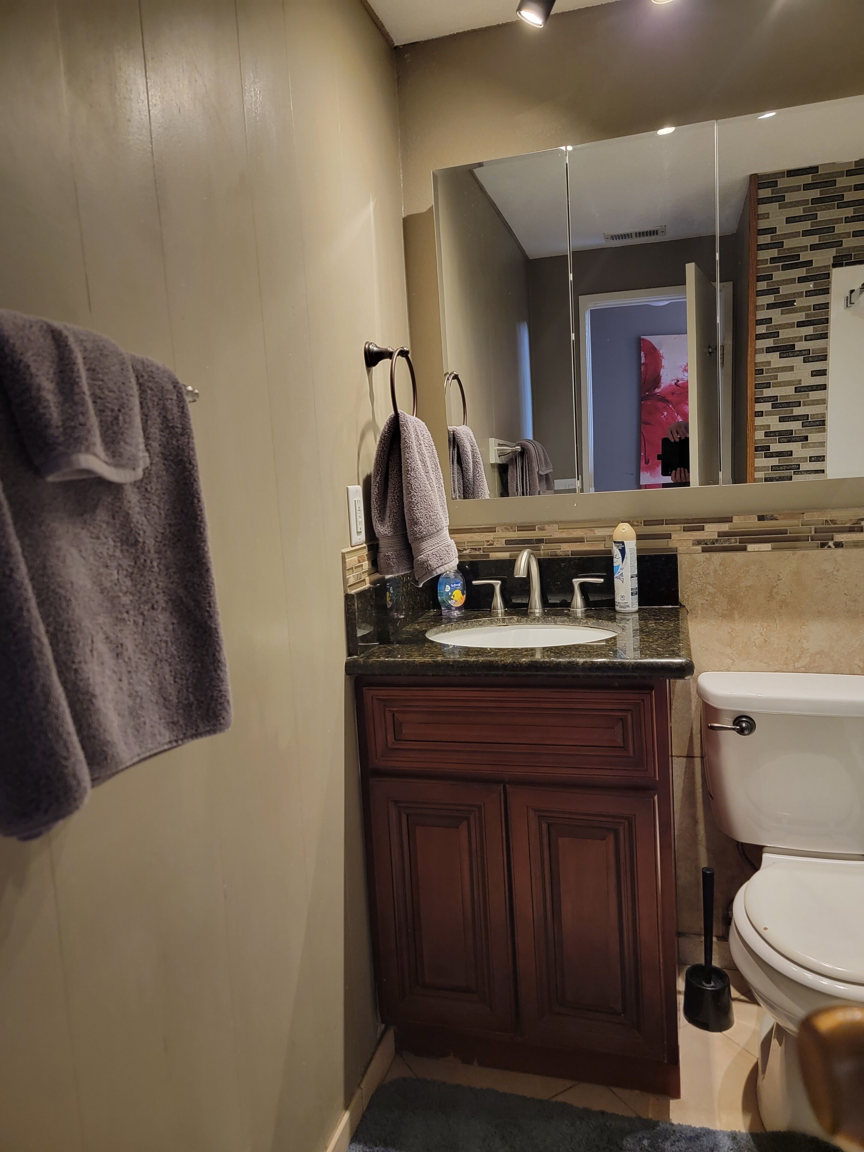 Un baño con lavamanos, espejo y retrete.