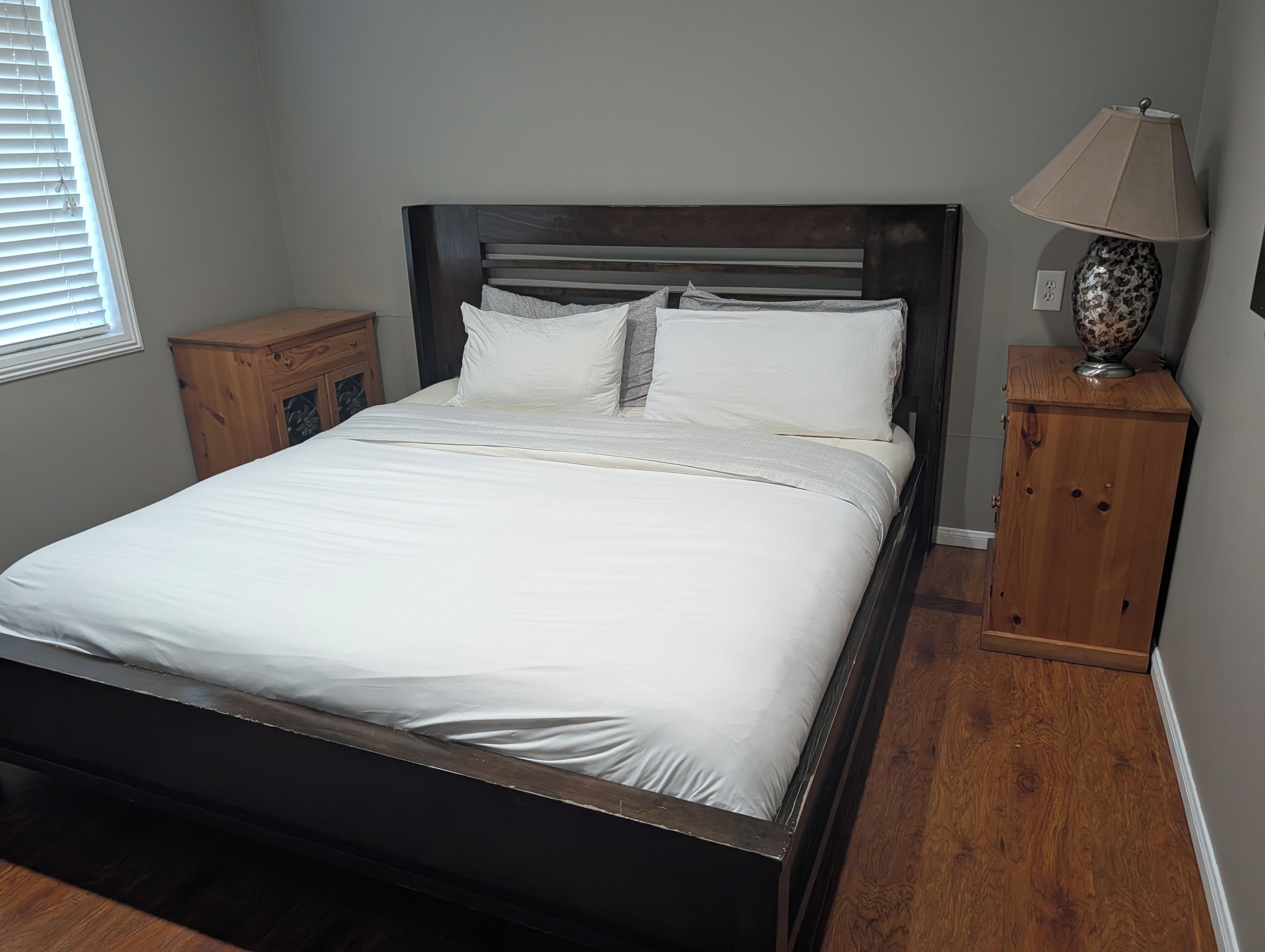 A bedroom with a bed, wooden headboard, bedside tables, and a lamp.