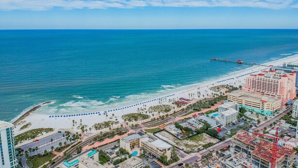 A coastal cityscape with a beach, a pier, and a hotel with multiple floors and balconies. - Dockside 504 with private balcony and beautiful views (Clearwater)