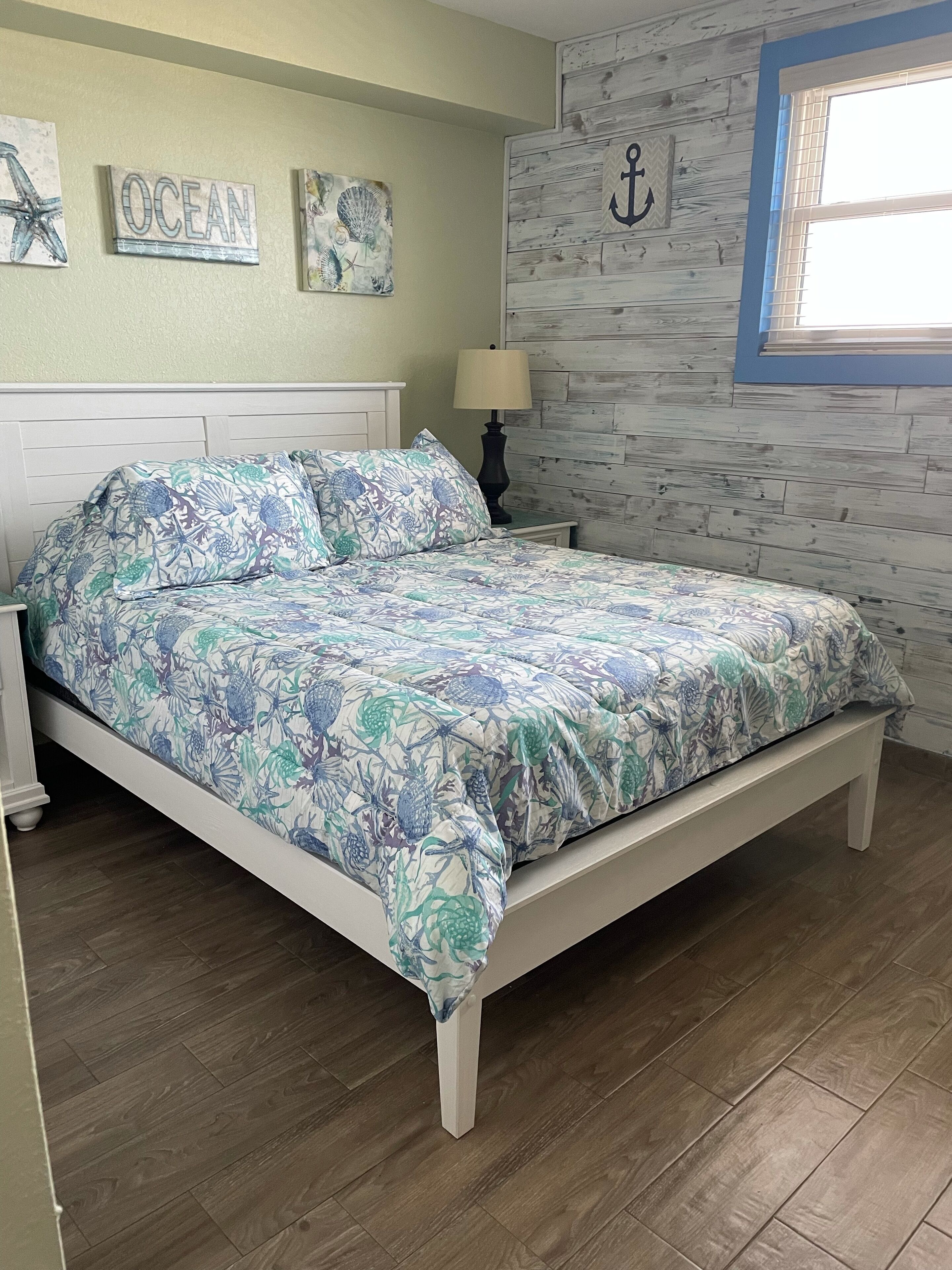 A bedroom with a bed, wooden headboard, and a nightstand with a lamp.