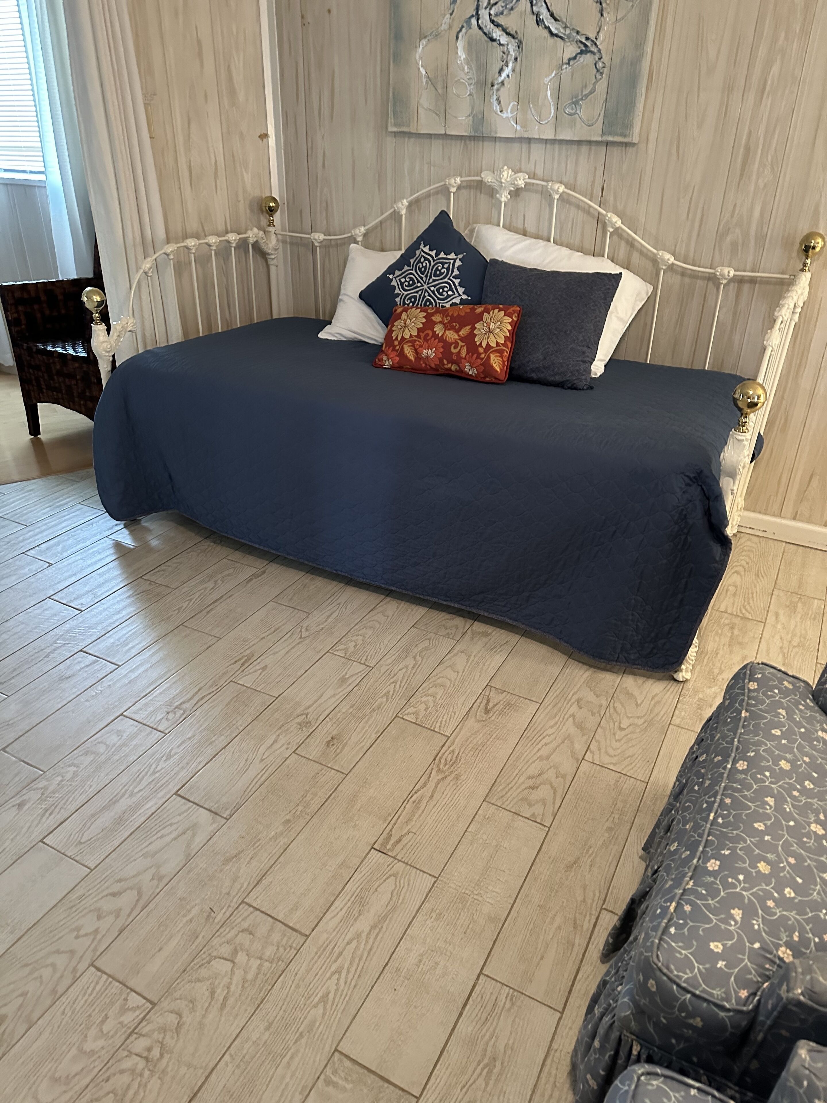 Un lit recouvert d’une couvre-lit bleu foncé, doté d’une tête de lit blanche et agrémenté de plusieurs coussins décoratifs.