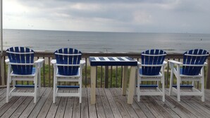 Eine Holzterrasse mit drei blauen Adirondack-Stühlen und einem kleinen Tisch.