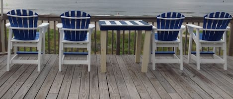 Une terrasse en bois avec trois chaises Adirondack bleues et une petite table.