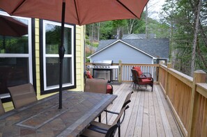 Eine Terrasse mit Tisch, Stühlen, einem Grill und einem Holgitter.