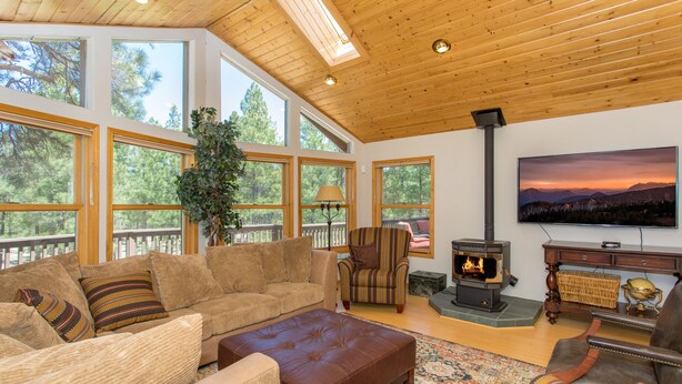 Una sala de estar acogedora con chimenea, asientos cómodos, ventanas amplias y un televisor.