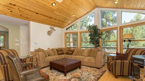 Una sala de estar acogedora con un sofá seccional grande, un sillón de cuero mecedor y una chimenea.