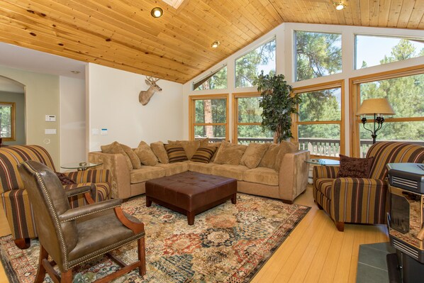 Una sala de estar acogedora con un sofá seccional grande, un sillón de cuero mecedor y una chimenea.