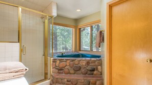 Un baño con pared de piedra, ducha y ventana con una toalla colgada.