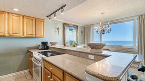 Una cocina moderna con encimeras de granito, armarios de madera, horno empotrado y una isla grande.