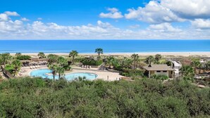 Un resort con piscina, palmeras y vista a la playa y el océano.