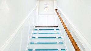 A staircase with white walls and blue steps leading to a door. - Beach Cottage Multiple Suites & Walk to Boardwalk! (Virginia Beach)