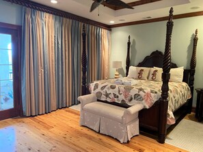 A bedroom with a four-poster bed, a bench, and a window with curtains.