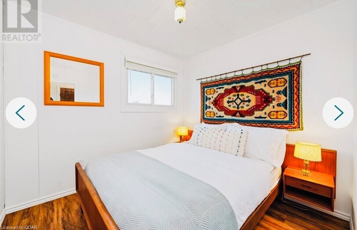 A bedroom with a bed, a mirror, a window, and a wall tapestry.