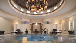 Un área de spa con una bañera de hidromasaje circular, sillones de descanso y una fuente central.