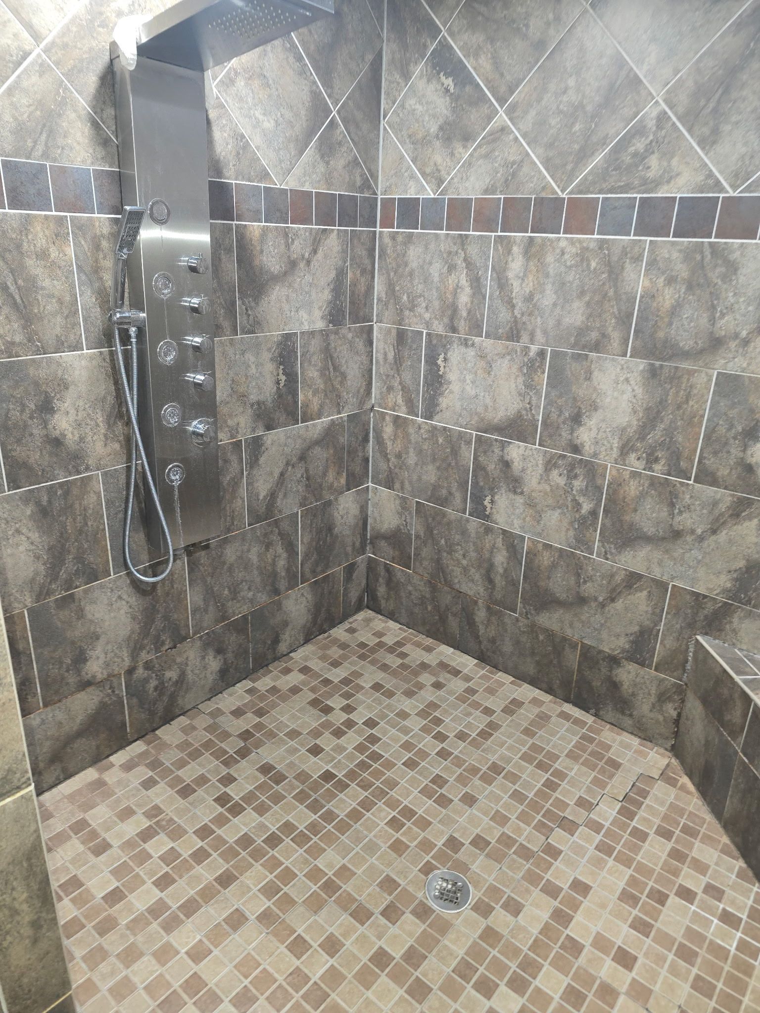 A shower area with a tiled floor and a showerhead.