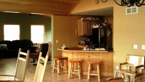 Een ruime woonkamer met keuken, houten meubels en een hoge plafond.