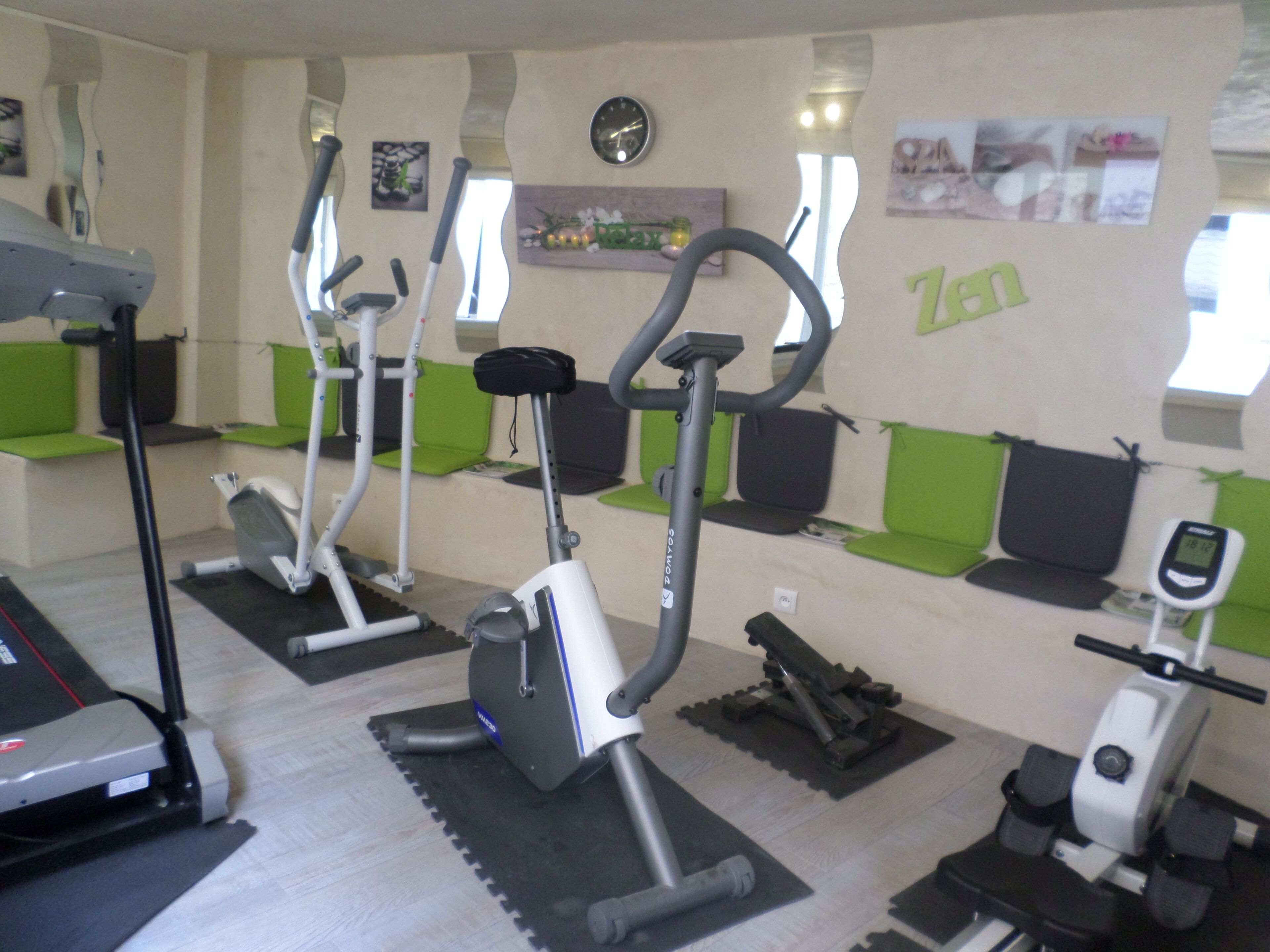 A gym with various exercise equipment, including treadmills, stationary bikes, and elliptical machines.