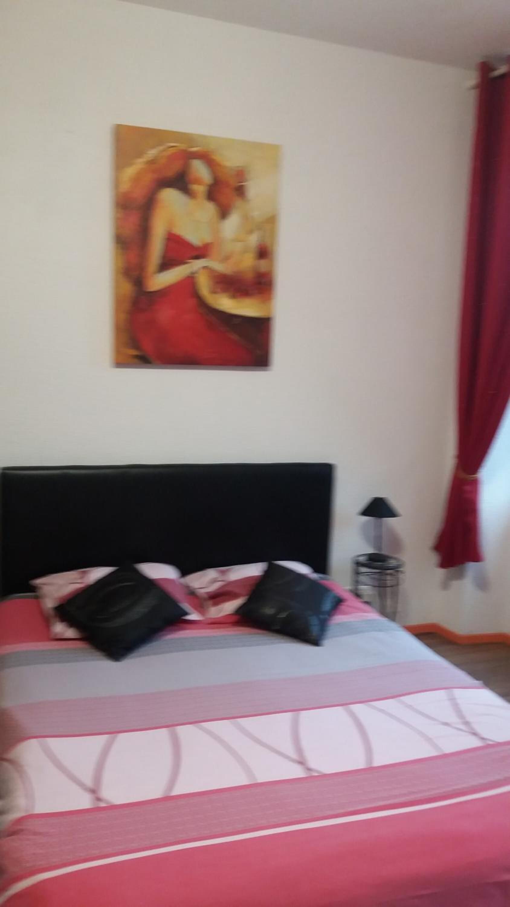 Ein Schlafzimmer mit Bett, Kissen, einer Lampe und einem Bild an der Wand.