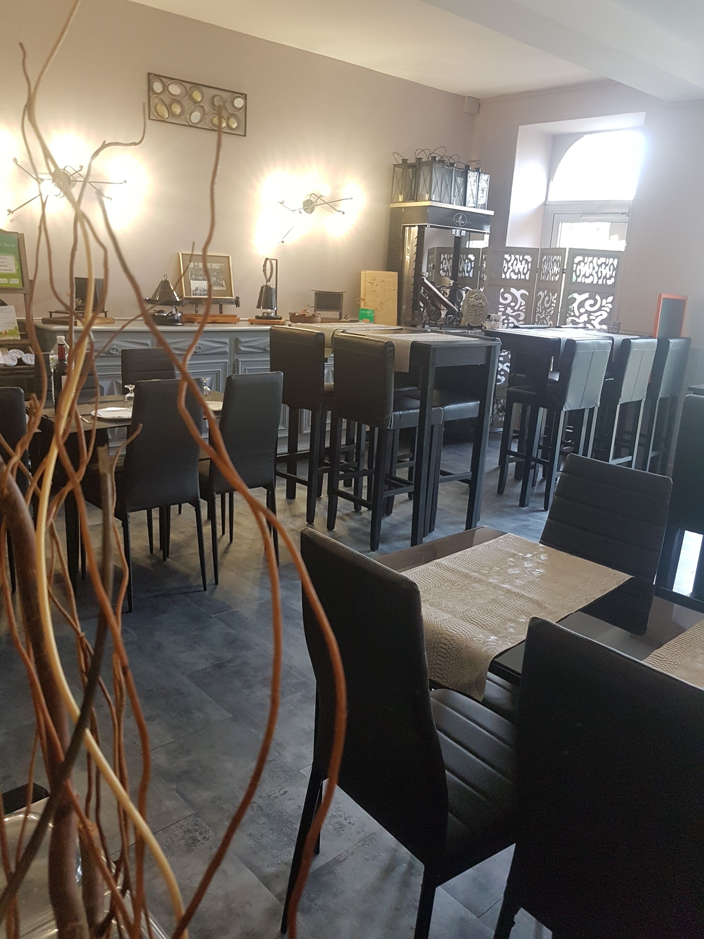 Un comedor con mesas y sillas, un área de cocina con electrodomésticos y decoración en la pared.