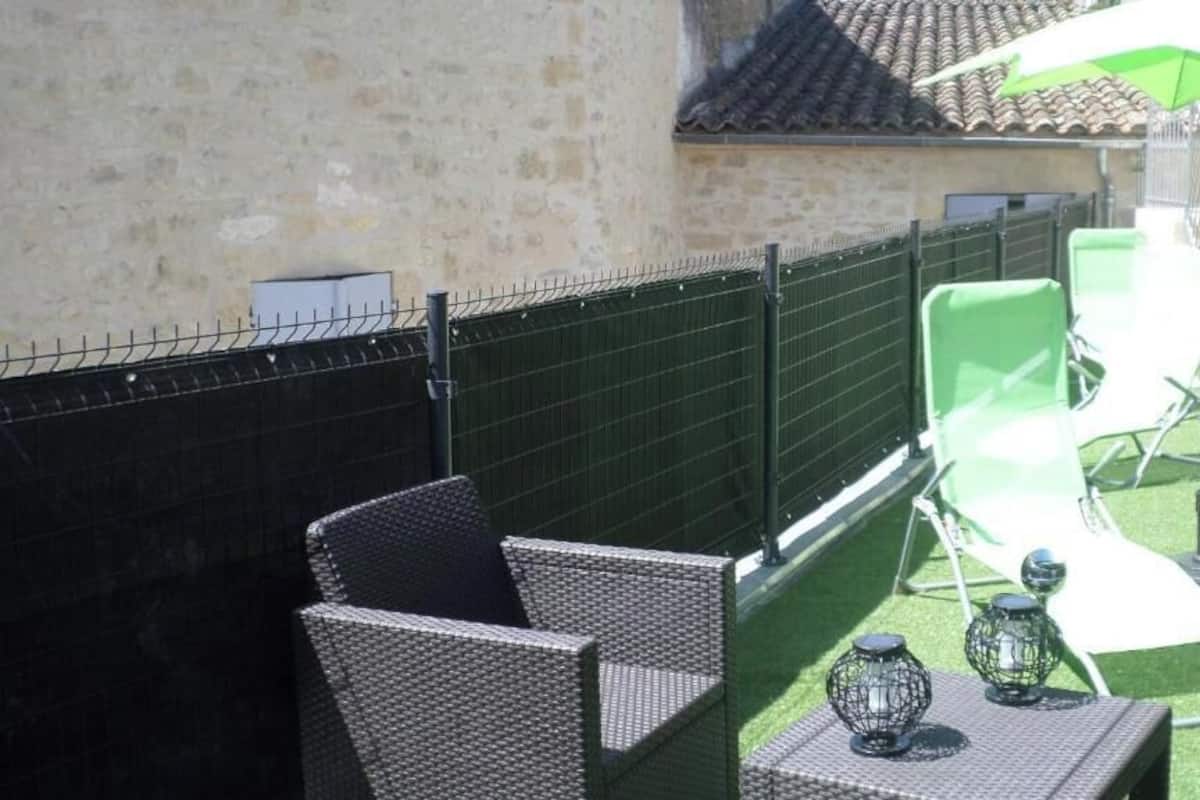 An outdoor patio area with wicker furniture, a green umbrella, and a small table with a decorative item.