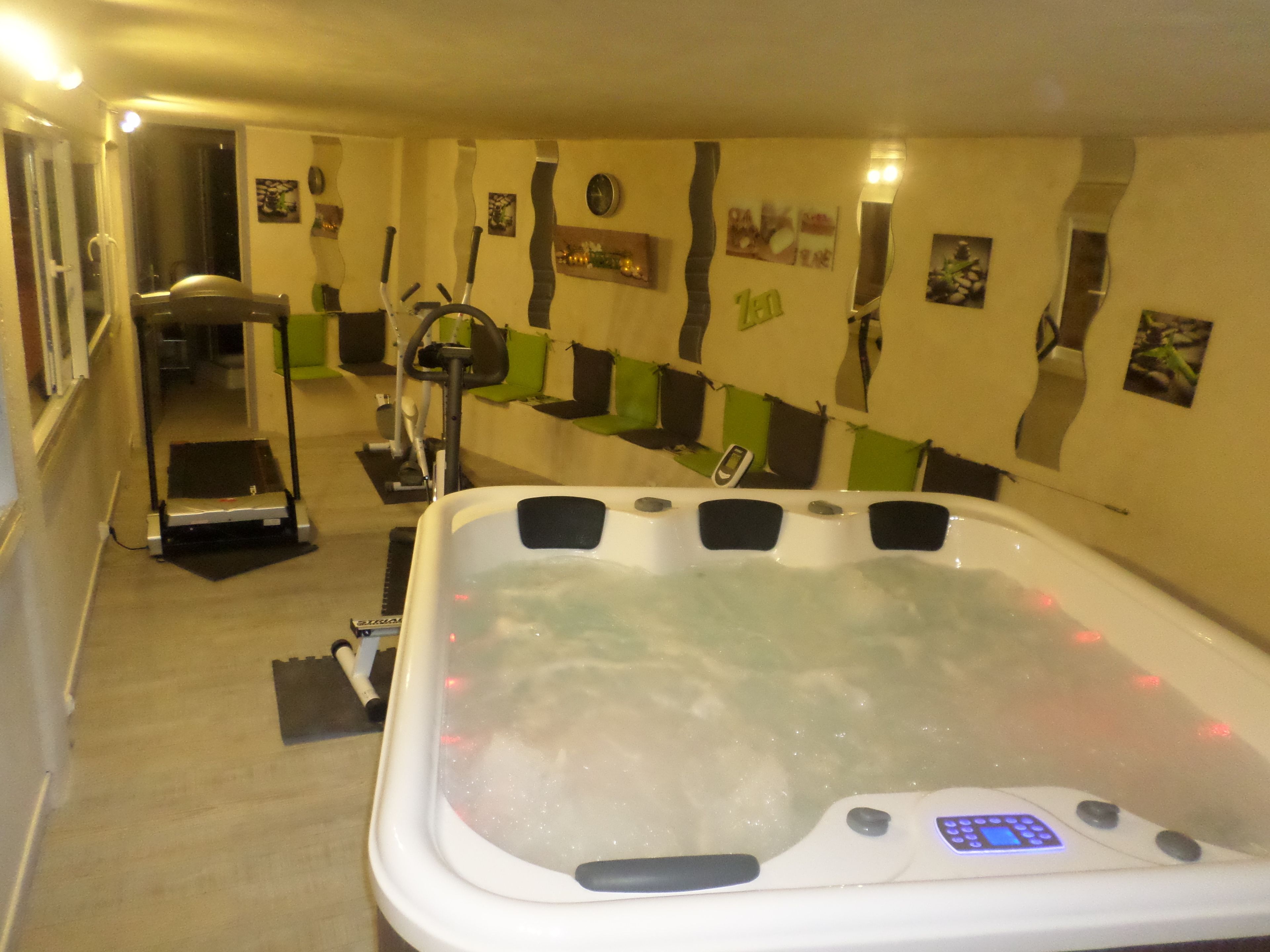 Une salle de spa équipée d’un jacuzzi, de matériel d’exercice et d’un mur décoré de différents éléments.