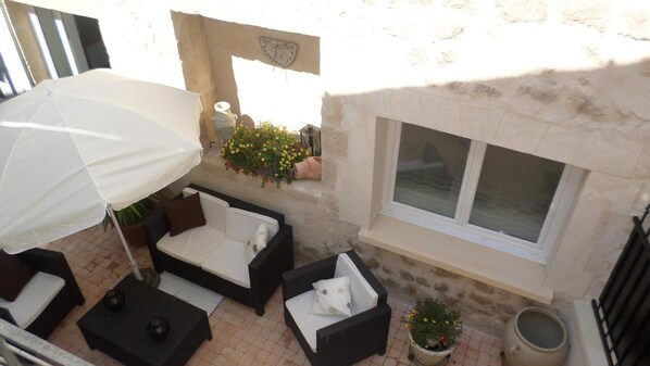 An outdoor seating area with a white umbrella, black and white furniture, and potted plants. - Appart'hôtel les Tilleuls (Saint-Macaire)