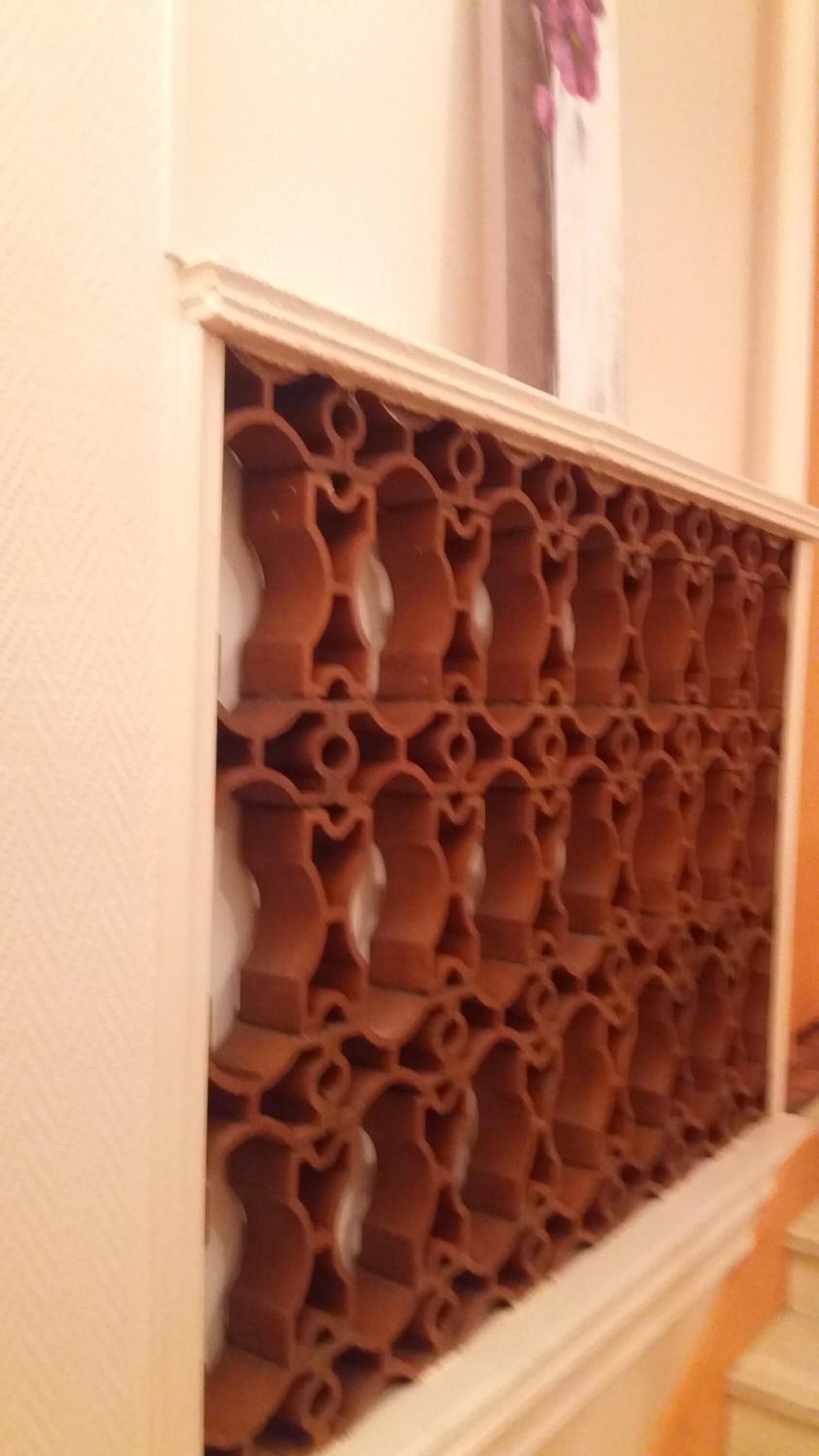 Eine Wand mit einem dekorativen Panel, das ein sich wiederholendes Muster aus ineinandergreifenden Formen zeigt.