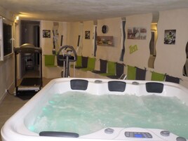 Quarto com uma grande banheira de hidromassagem, esteira e equipamentos de ginástica.