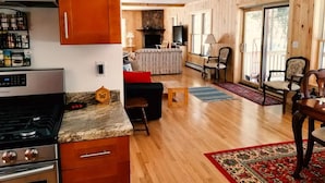 A spacious living area with a kitchen, wooden walls, and a fireplace. - Balsam Point Lakehouse · Indian Lake Adirondacks · Waterfront on Lake Abanakee (Indian Lake)