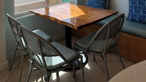 Un coin repas avec une table en bois et des chaises en osier, une vue sur la plage et un tableau accroché au mur.