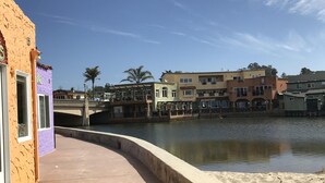 Une promenade en bord de mer avec une passerelle en béton incurvée, un pont et des bâtiments en arrière-plan.