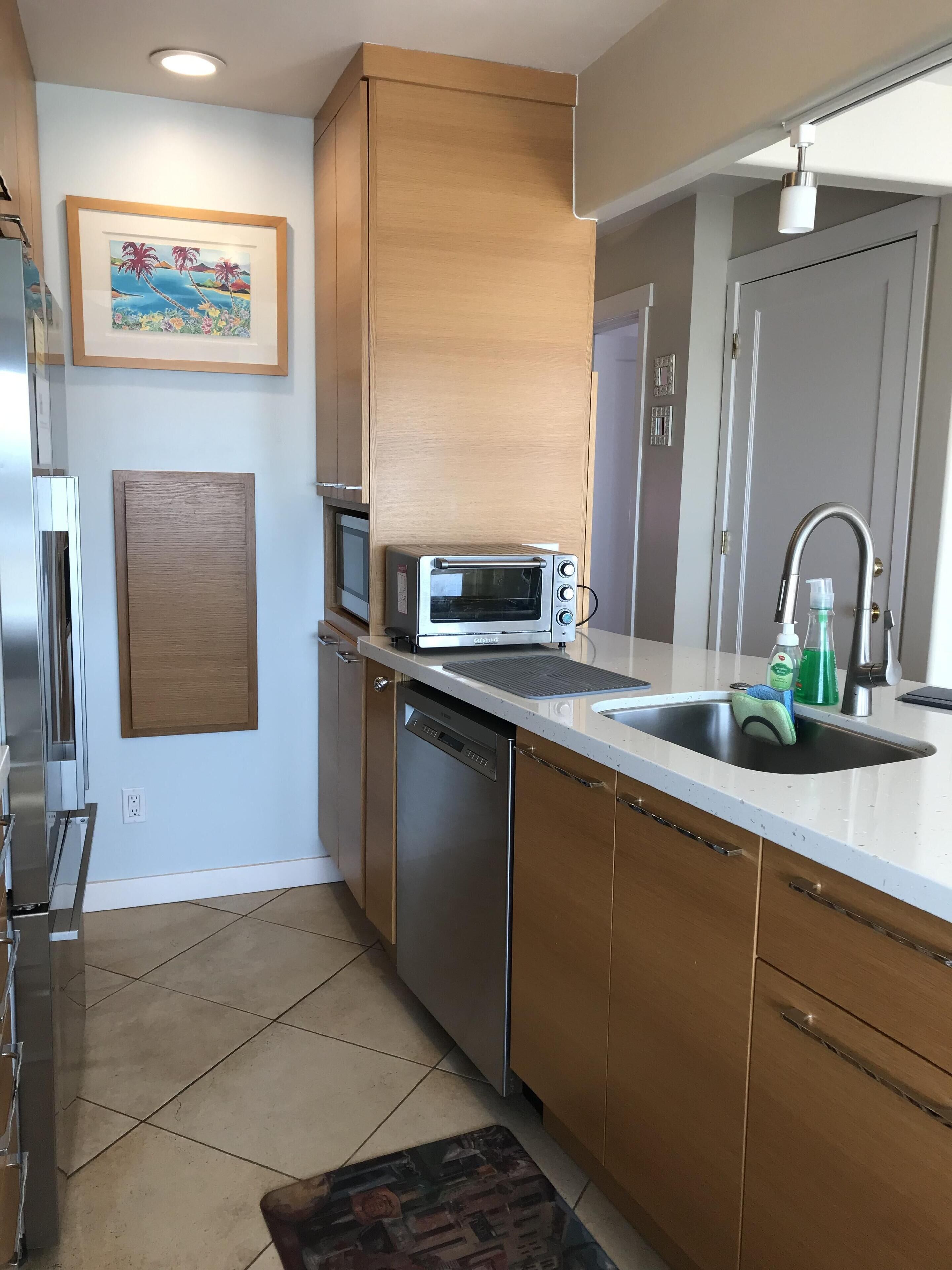 A modern kitchen with a built-in microwave, dishwasher, and stainless steel sink.