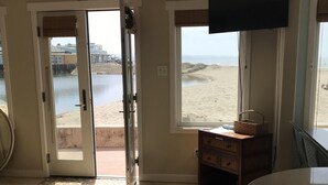 Une chambre avec vue sur la plage, une télévision, un meuble en bois et un sol carrelé orné d’un motif en mosaïque.
