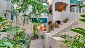 A multi-level building with a central staircase surrounded by lush tropical plants.