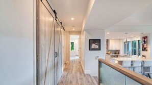 A modern kitchen with a central island, a dining area with bar stools, and a view of the outdoors.
