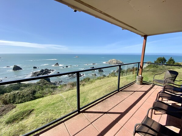 Un balcon avec vue sur l’océan, comprenant un espace gazonné et un coin salon.
